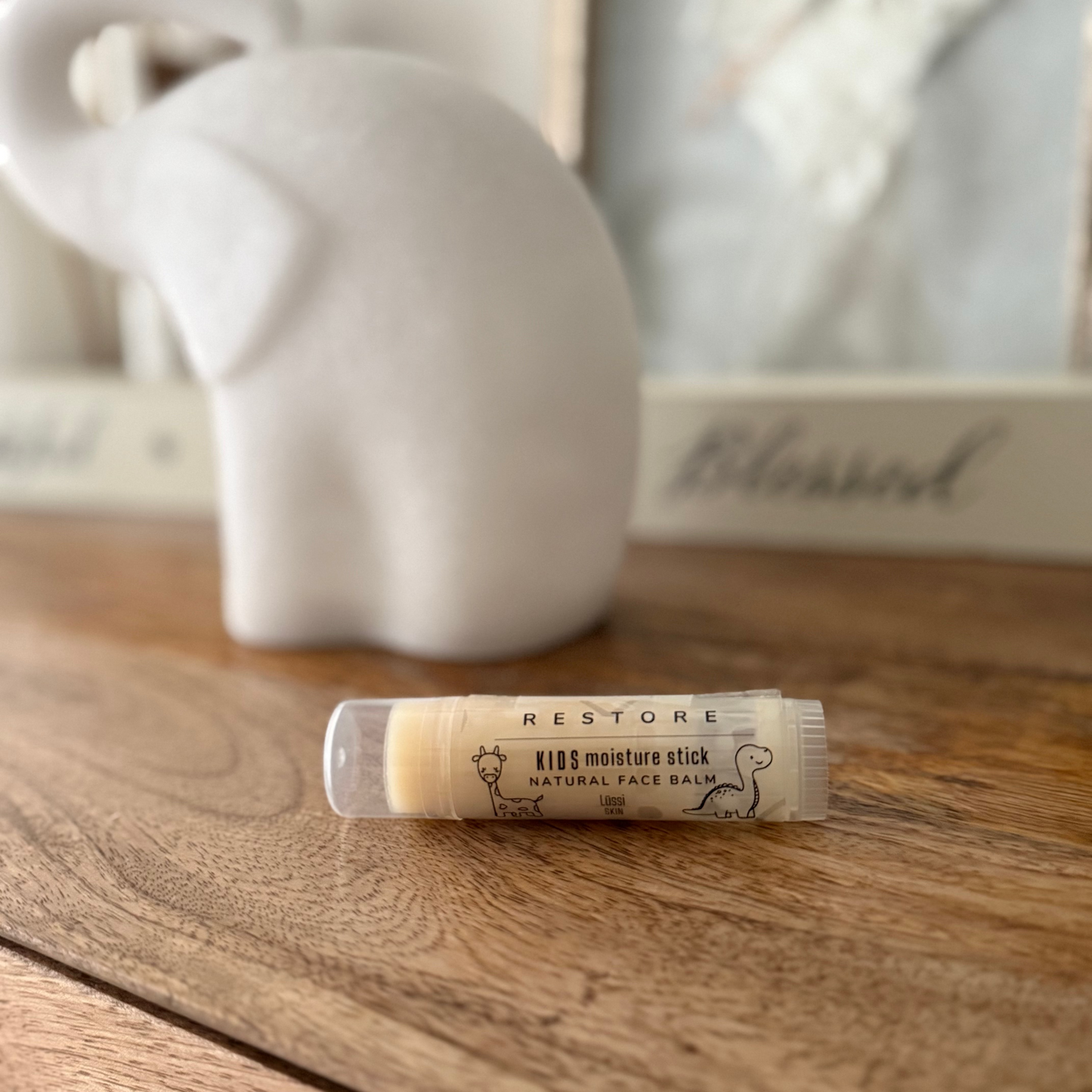 KIDS moisture stick on a wooden surface with a blurred background. Fragrance Free.