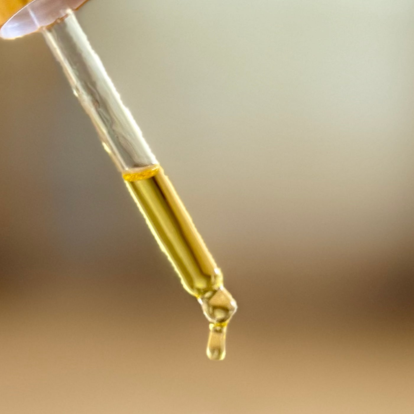 Close-up of a dropper with a rich, gold serum.