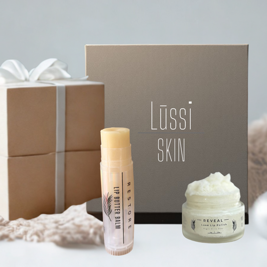 Holiday gift set that includes a creamy, neutral colored lip scrub in a glass jar and a large lip balm in a tube.