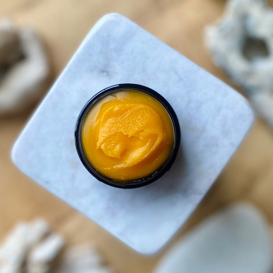 A jar containing anti aging orange-colored, vitamin c, turmeric face balm for glowing skin.